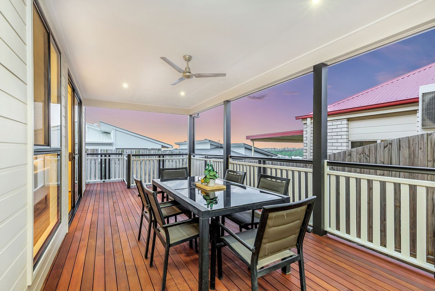 Spacious outdoor timber deck with dining setting and stunning sunset sky views.
