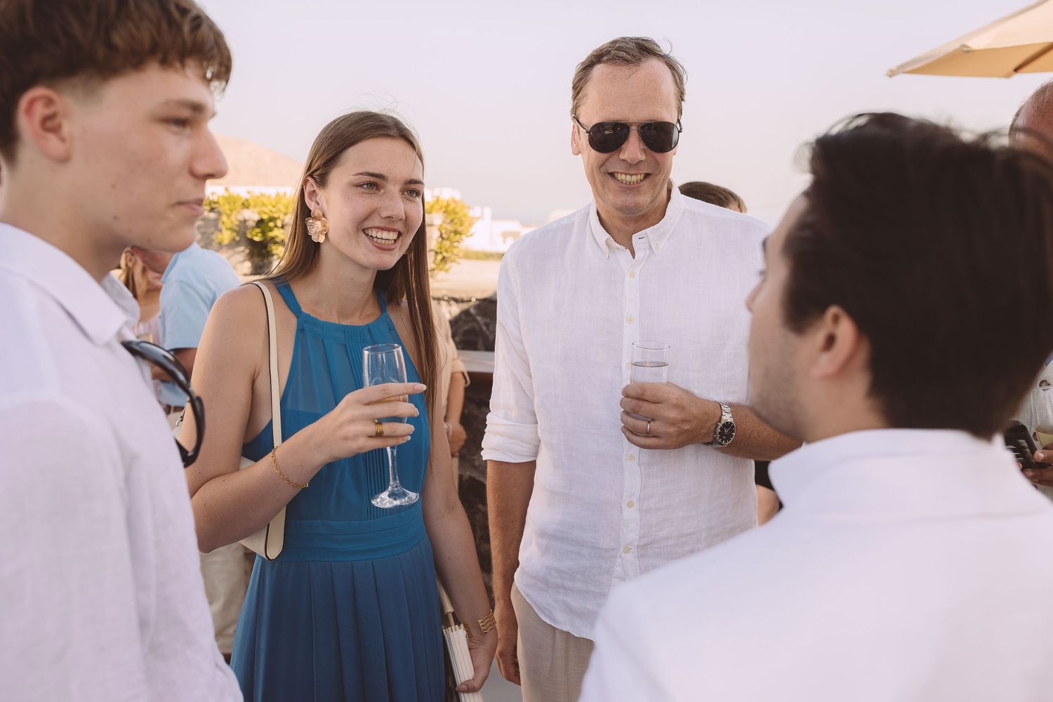 Wedding guests enjoying drinks and conversation at an outdoor destination wedding on a sunny day in Santorini.