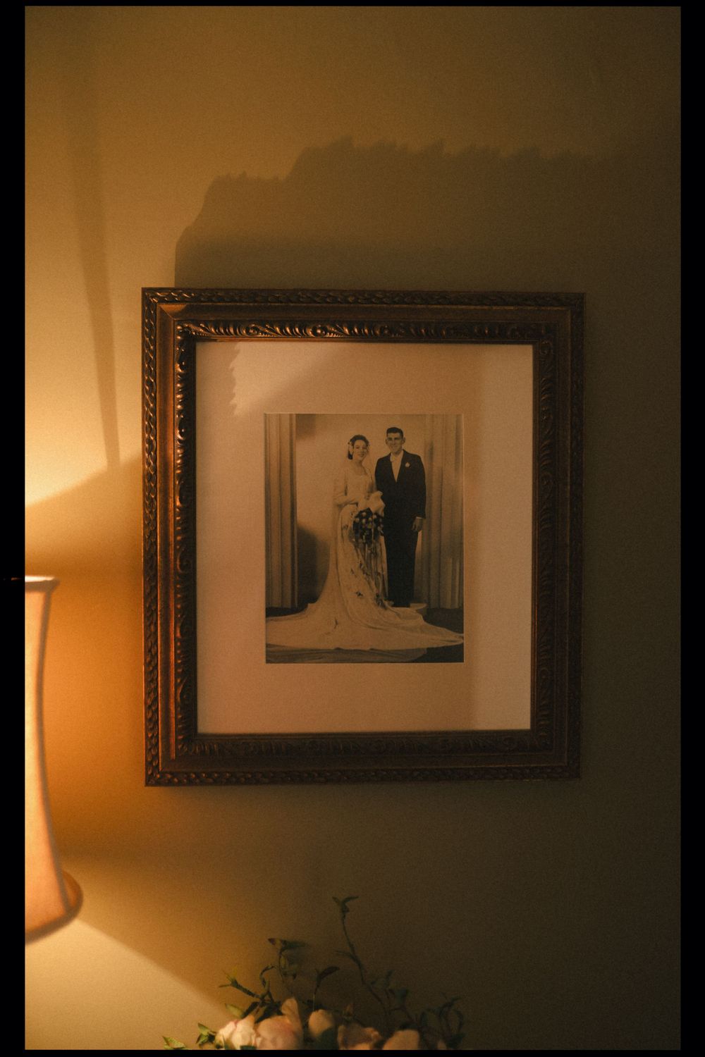 A series of vintage black and white photographs in ornate frames displayed on a warmly lit wall with decorative elements below.