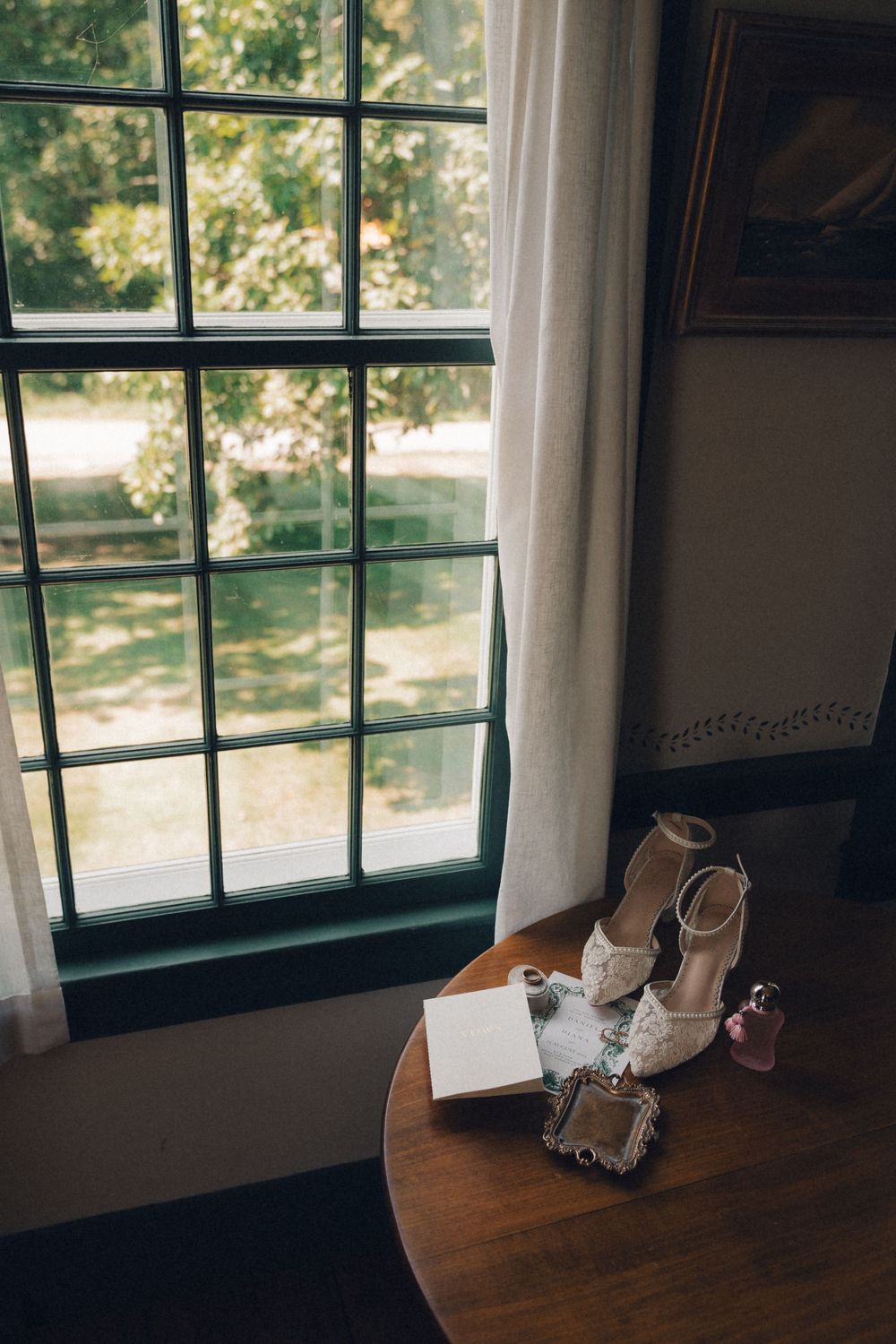 Wedding shoes and accessories arranged on a wooden windowsill in natural light.