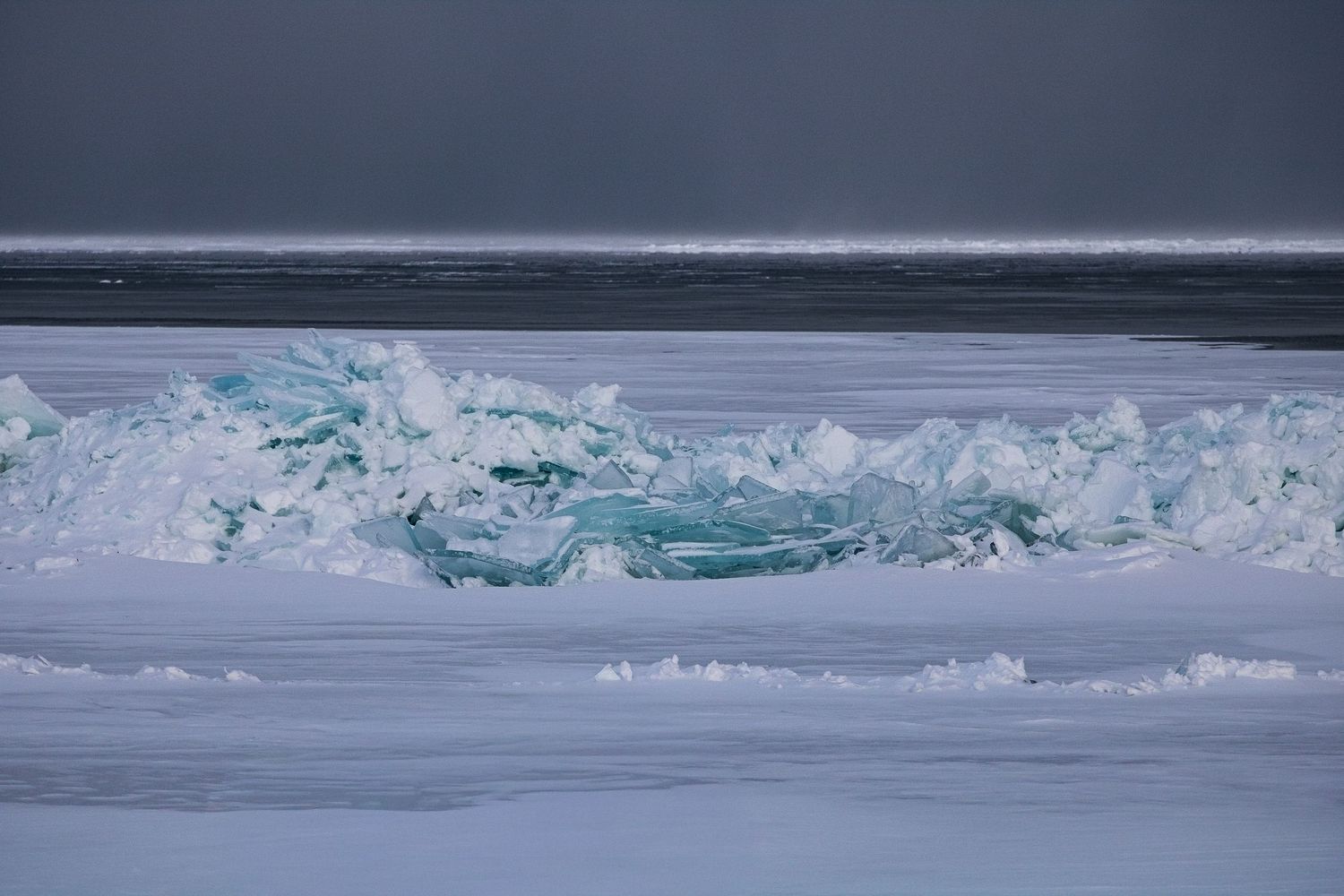 A panoramic view of arctic sea ice with jagged formations stretching across the frozen landscape under cloudy skies.