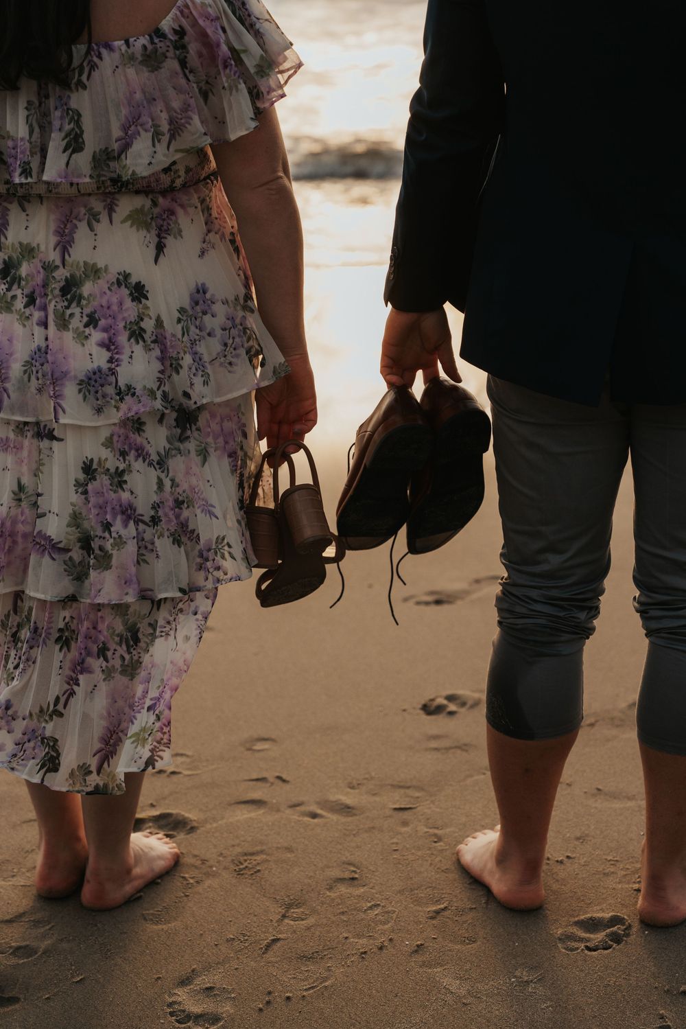 Bare feet and sandals walk along sandy beach at sunset creating intimate beach photography composition.