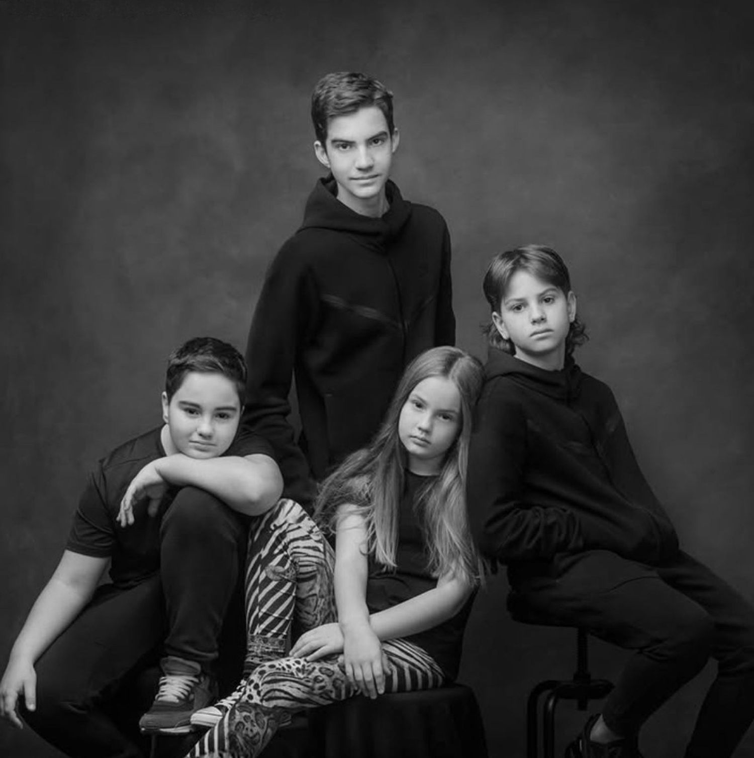 Black and white panoramic photo showing five people sitting casually against a wall.