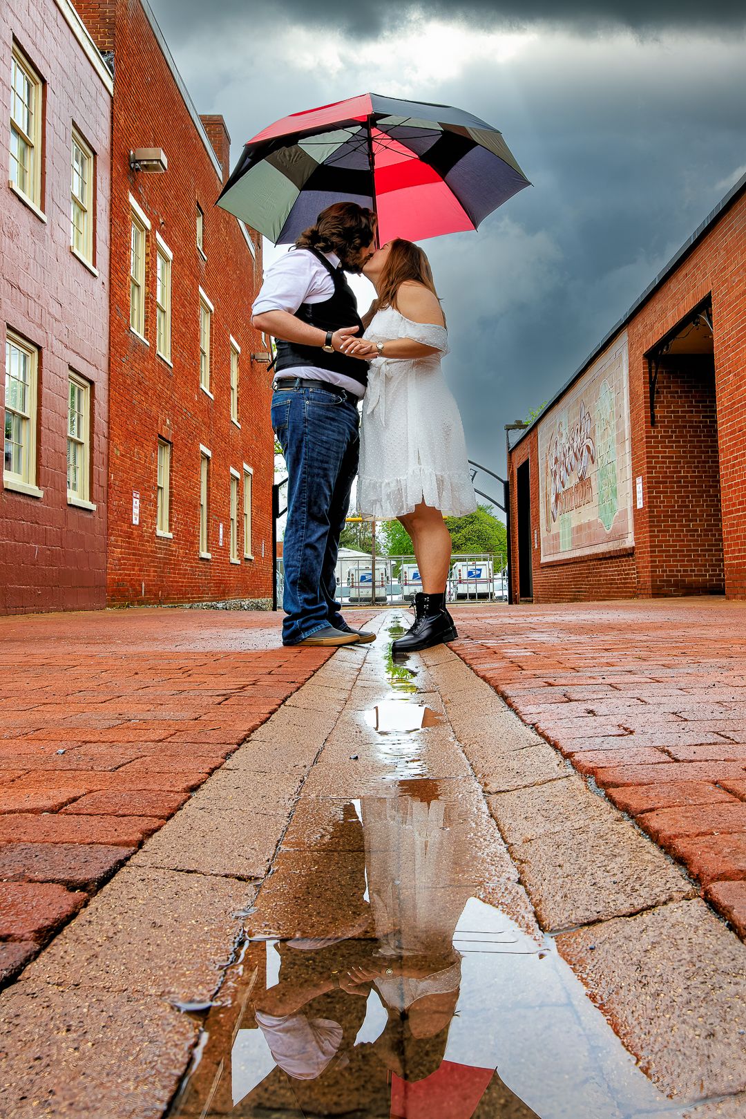 A series of puddle reflections on brick pavement showing people with umbrellas during a rainy day.