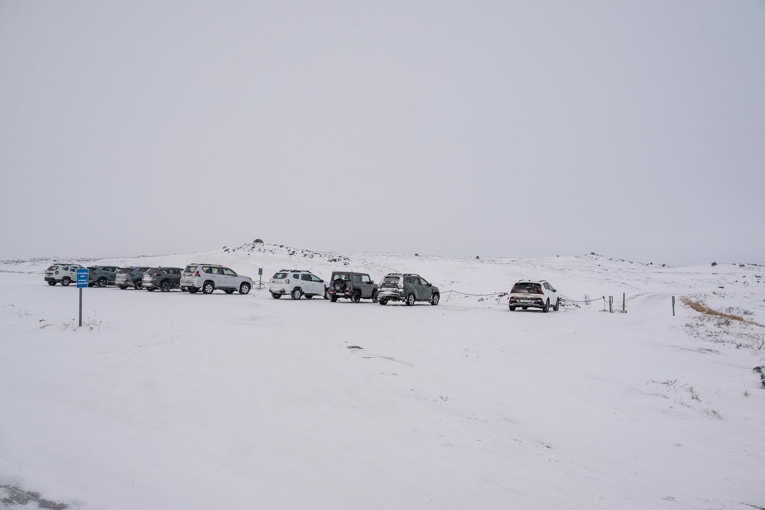 Vehicles traverse through a vast snowy landscape with snow-covered mountains visible in the distance.