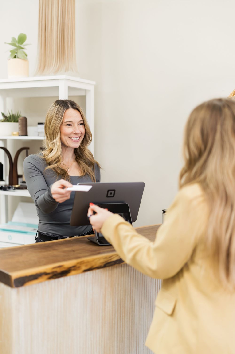Professional transaction taking place at a modern white reception desk between staff member and client.
