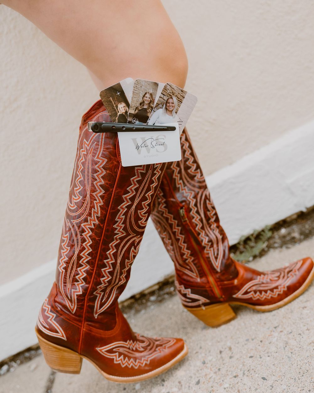A pair of intricately embroidered brown leather cowboy boots with decorative stitching and pointed toes on a light surface.