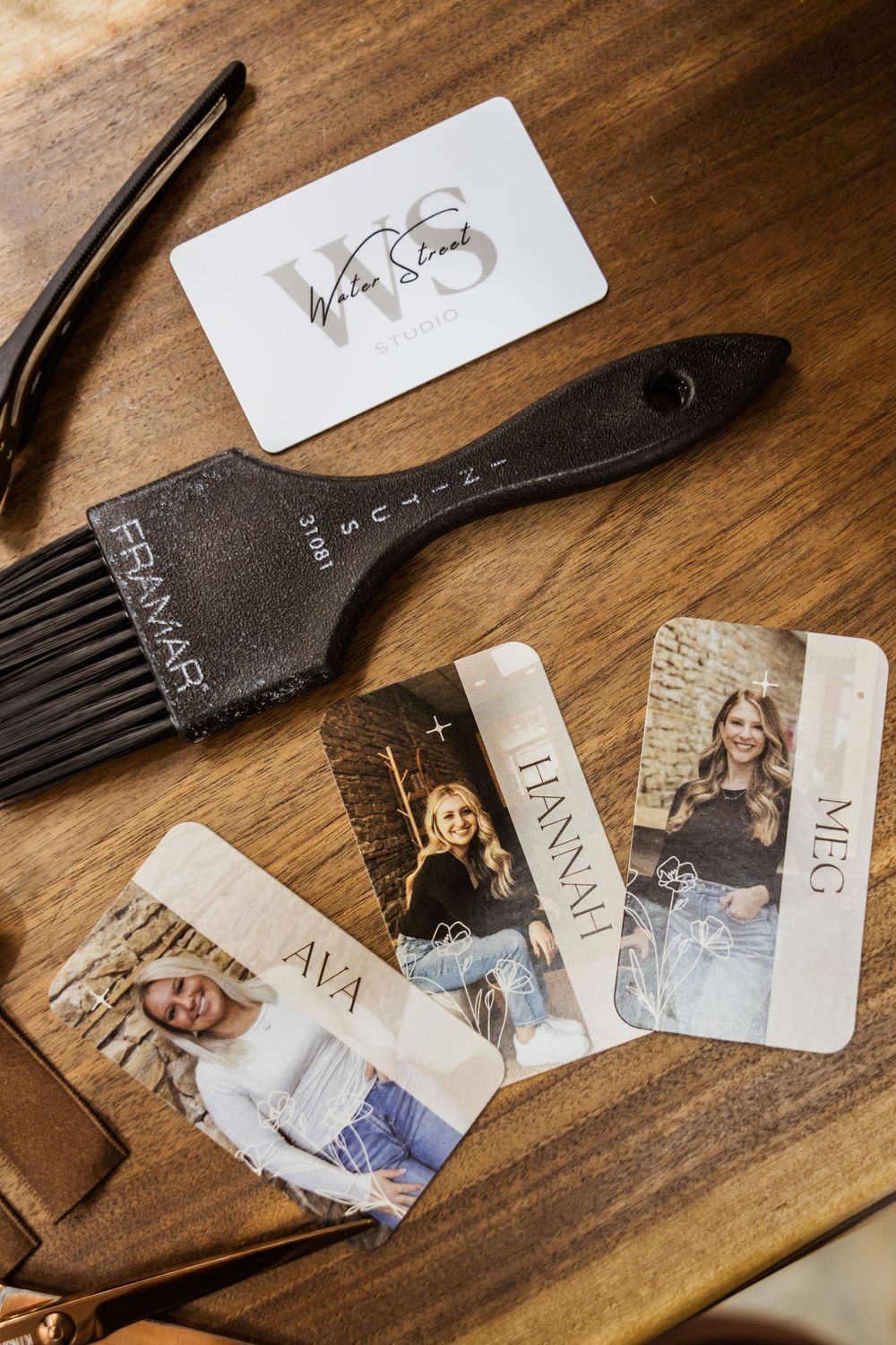 Professional hair styling tools including a black brush and salon membership cards arranged on a wooden surface.