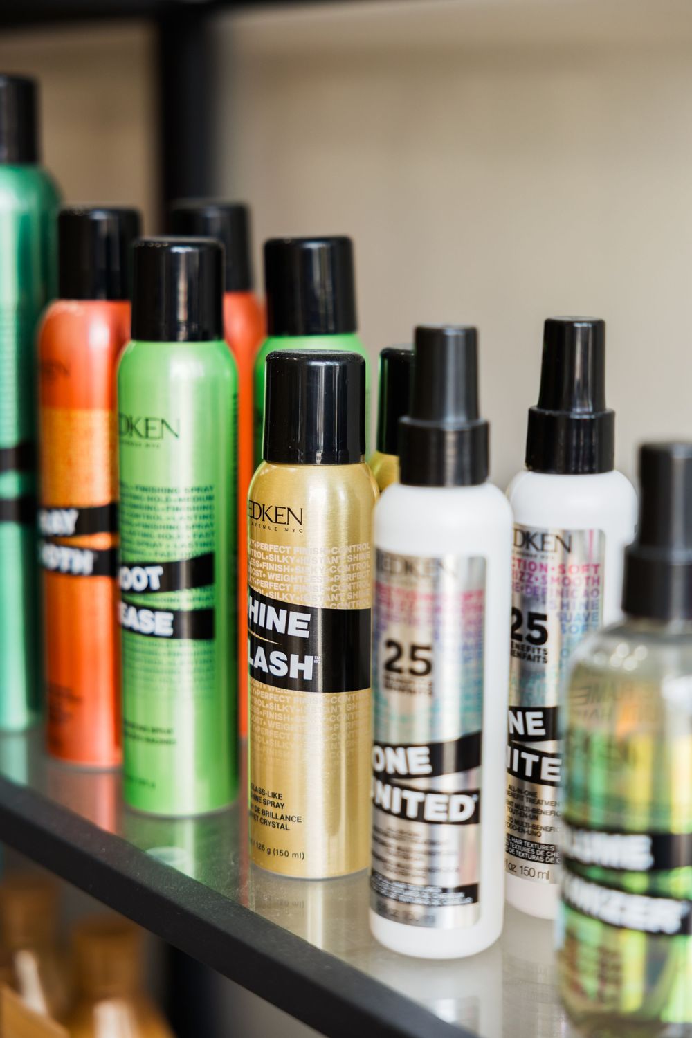 Professional hair care products from Redken including styling sprays and treatments displayed on a shelf.