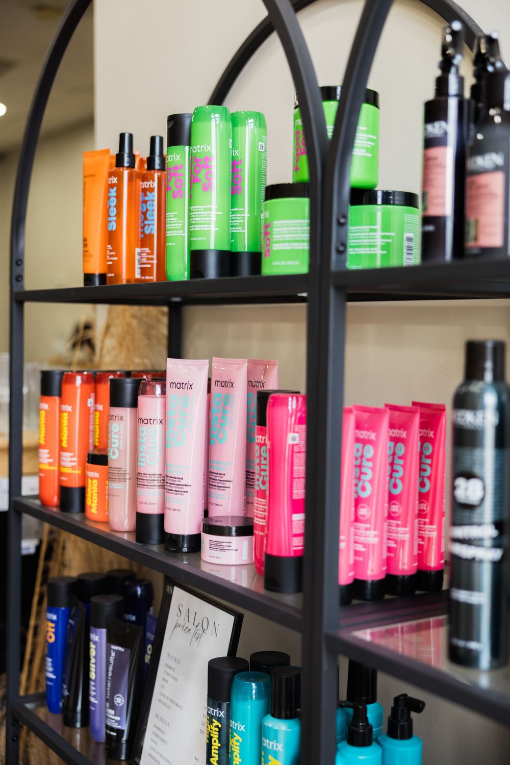 Colorful hair styling products arranged on black metal shelves in a salon retail display.