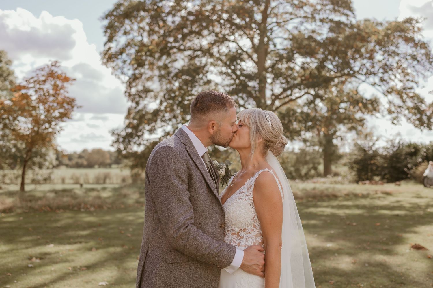 Romantic outdoor wedding photography session in a rustic field with autumn trees in the background.