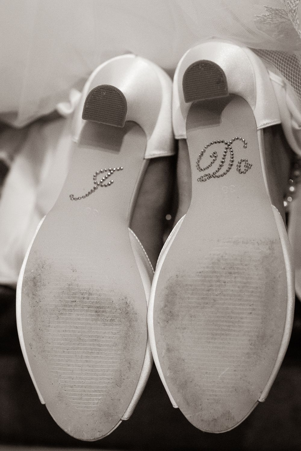 Wedding shoes with 'I Do' crystals on the soles shown in black and white photography.