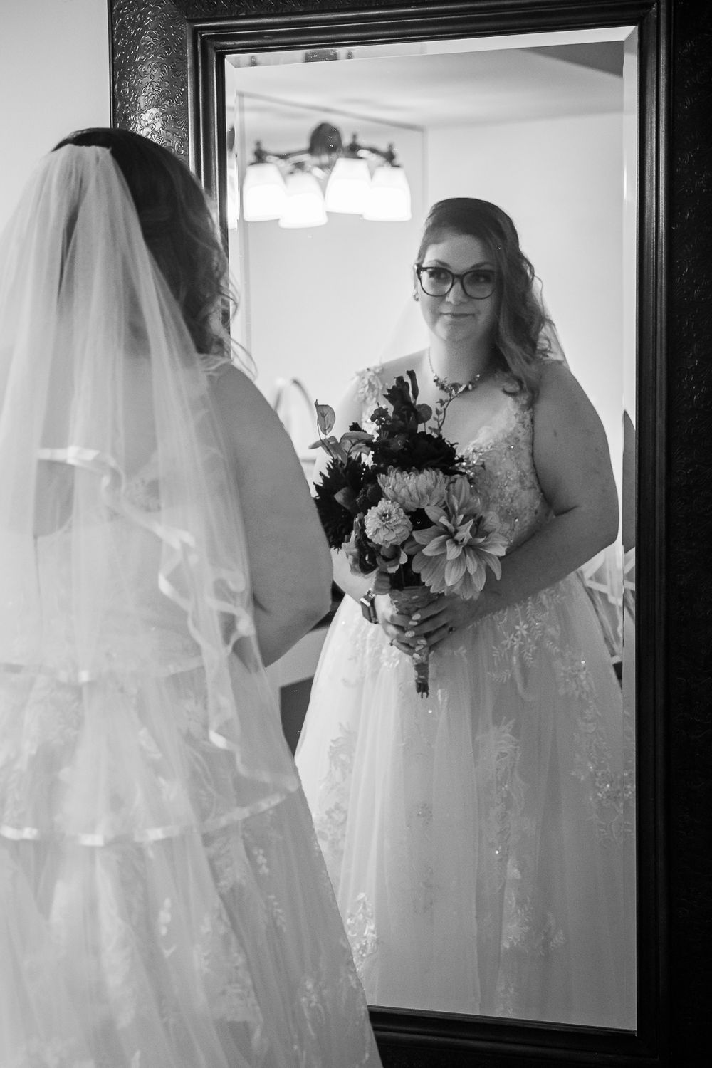 Black and white wedding photos show a bride in a flowing white dress and veil preparing for her special day.