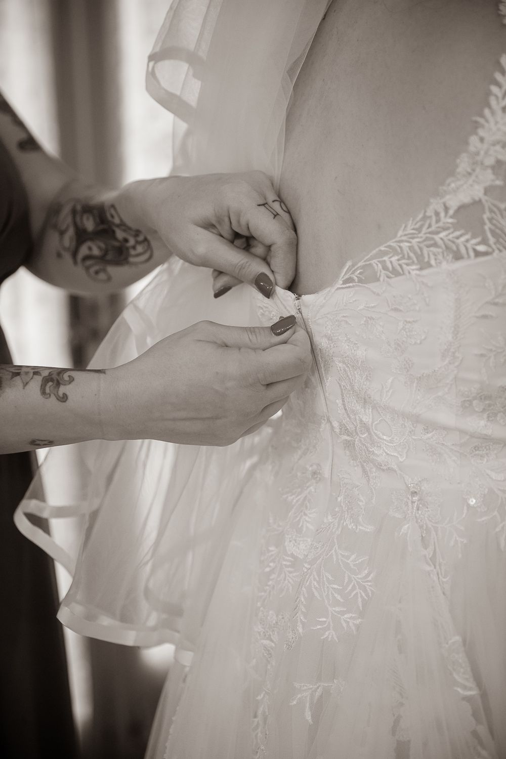 Close-up details of delicate white lace and beading on a wedding dress in black and white photography.