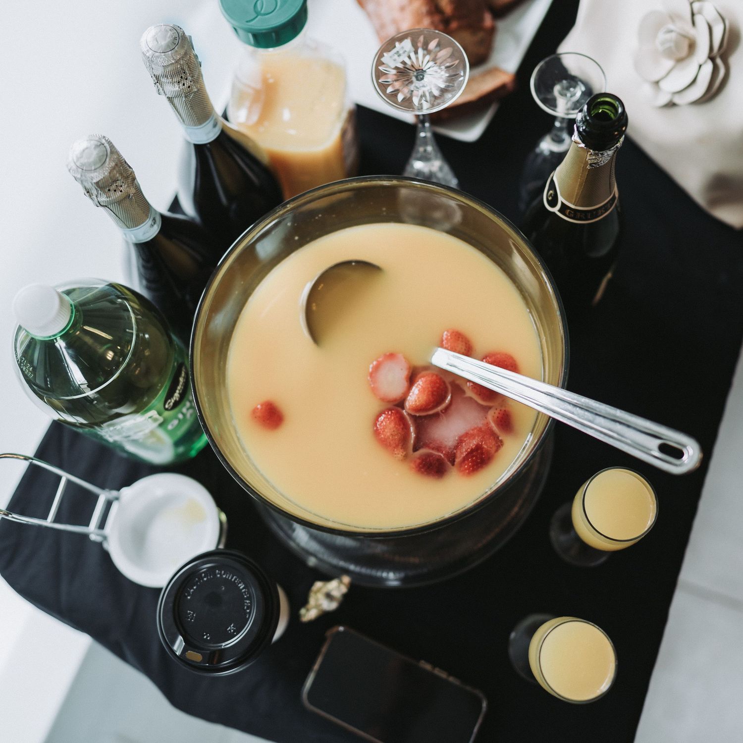 Homemade cheese fondue with melted gruyere and white wine being prepared in multiple stages on a dark surface.