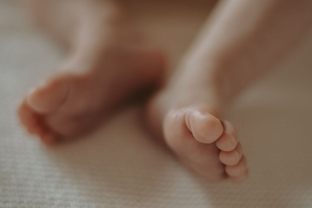 Macro shot of tiny baby feet resting on white textured fabric.