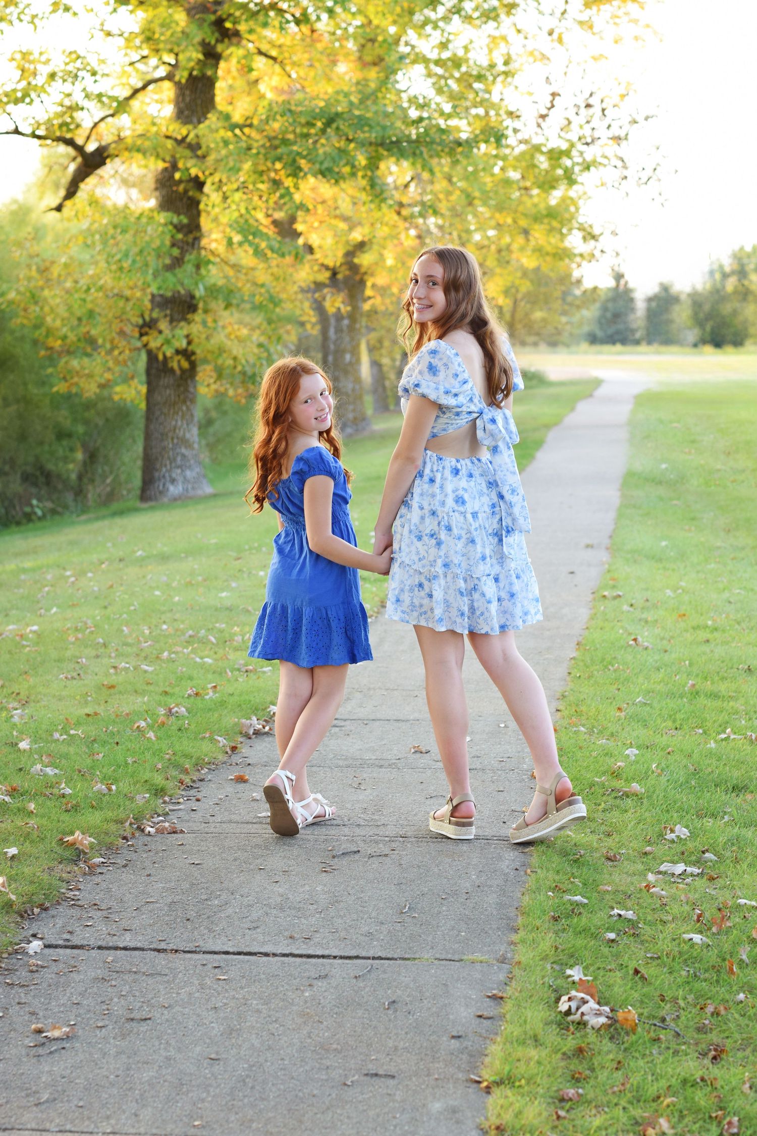 Children playing and walking along a tree-lined path with golden autumn leaves.