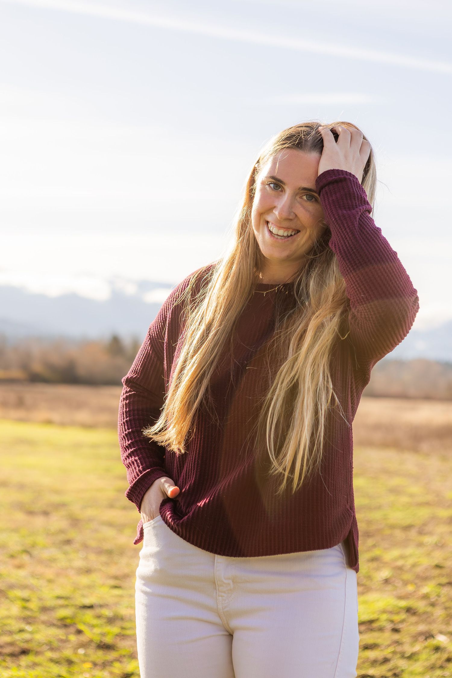 Portrait session in golden sunlight with burgundy sweater and white pants.