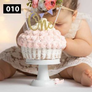 Pink rosette decorated cake with gold 'One' topper and floral accents.