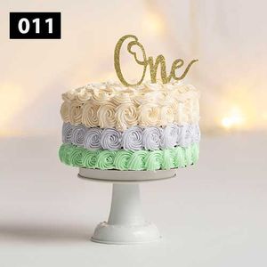 White and mint green rosette cake with gold 'One' topper on white stand.