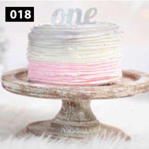 Elegant cake with pink ombre frosting displayed on a rustic wooden cake stand.