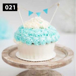 White cake with turquoise frosting details and mini bunting decoration on rustic stand.