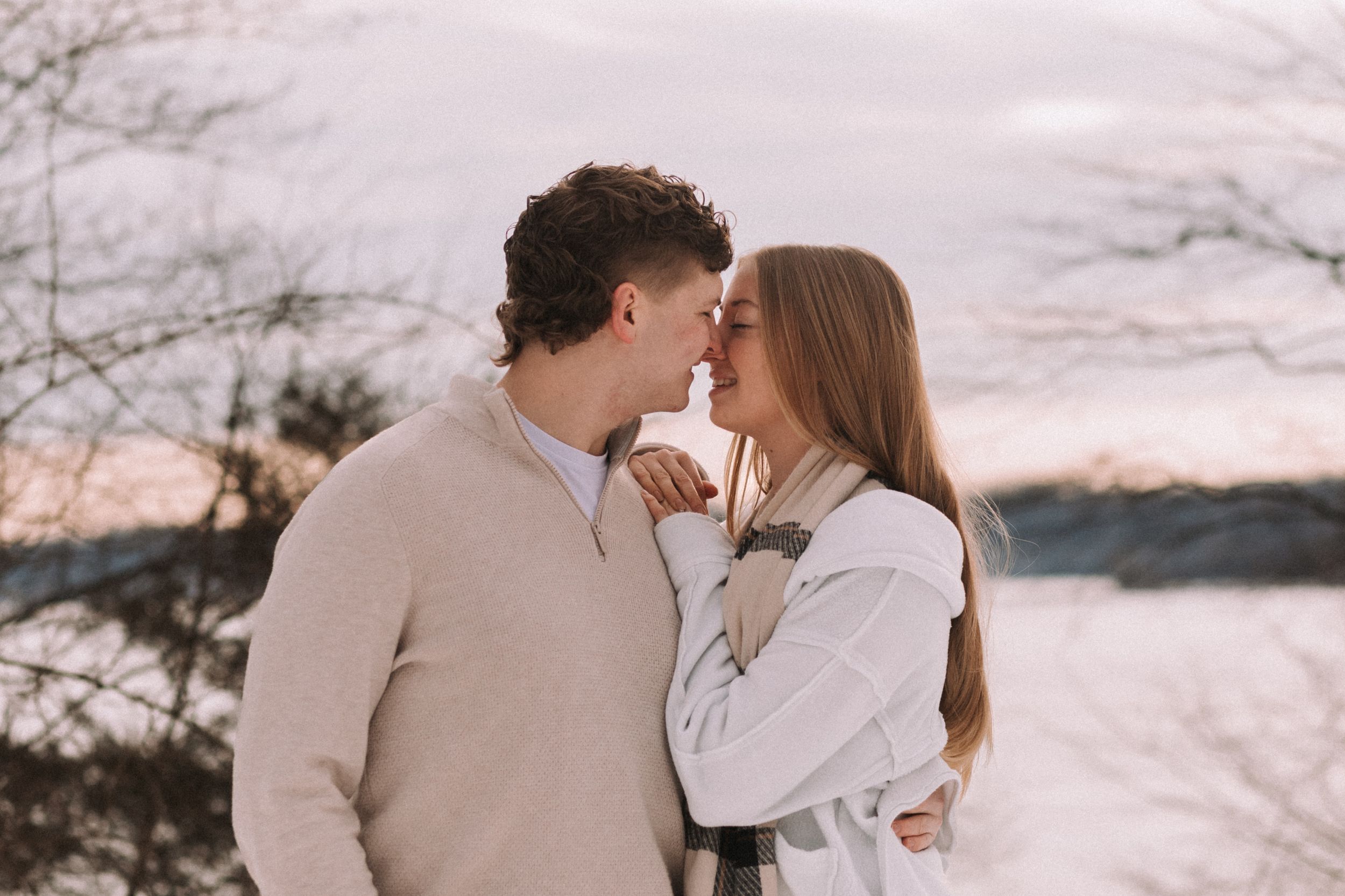 Romantic couple shares intimate moments in a series of winter sunset photos with snowy landscape backdrop.