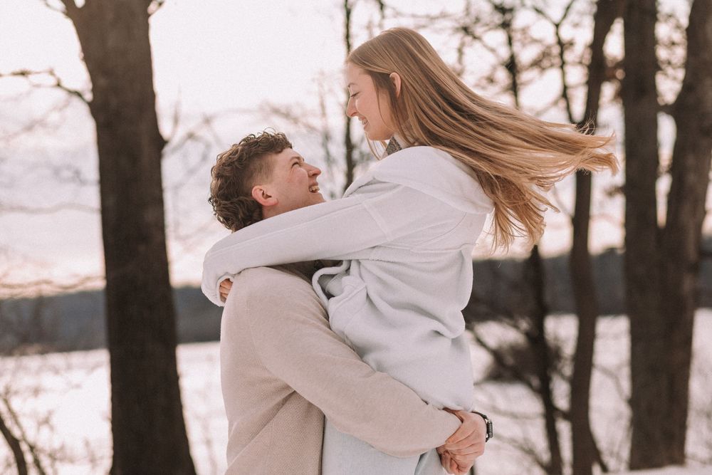 A romantic moment captured between two people hugging against a snowy winter backdrop.