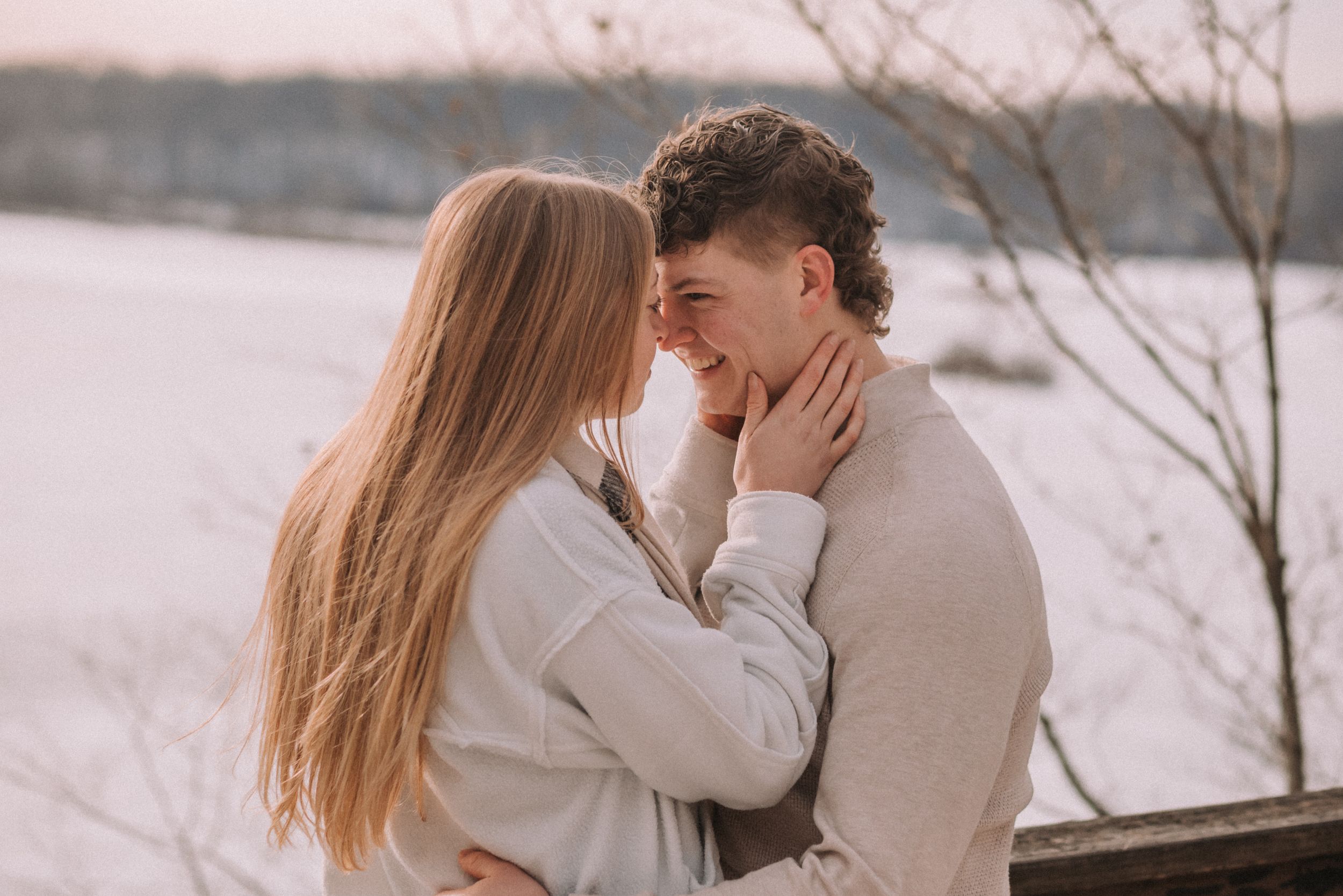 A tender embrace shared between a couple during a snowy winter photoshoot outdoors.