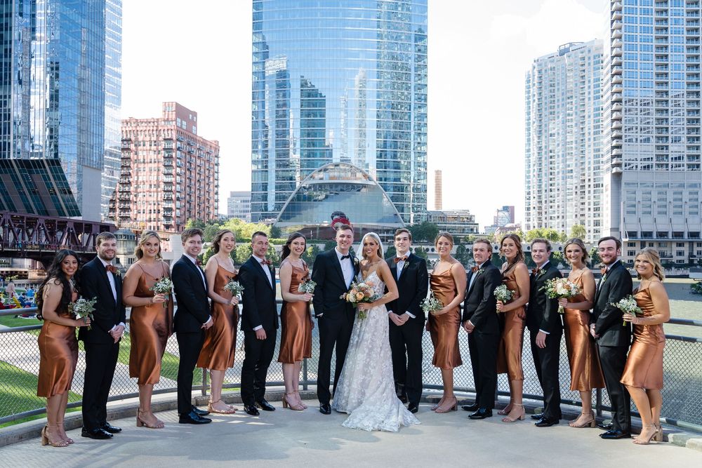 Wedding party poses together in front of modern glass skyscrapers in downtown Chicago.