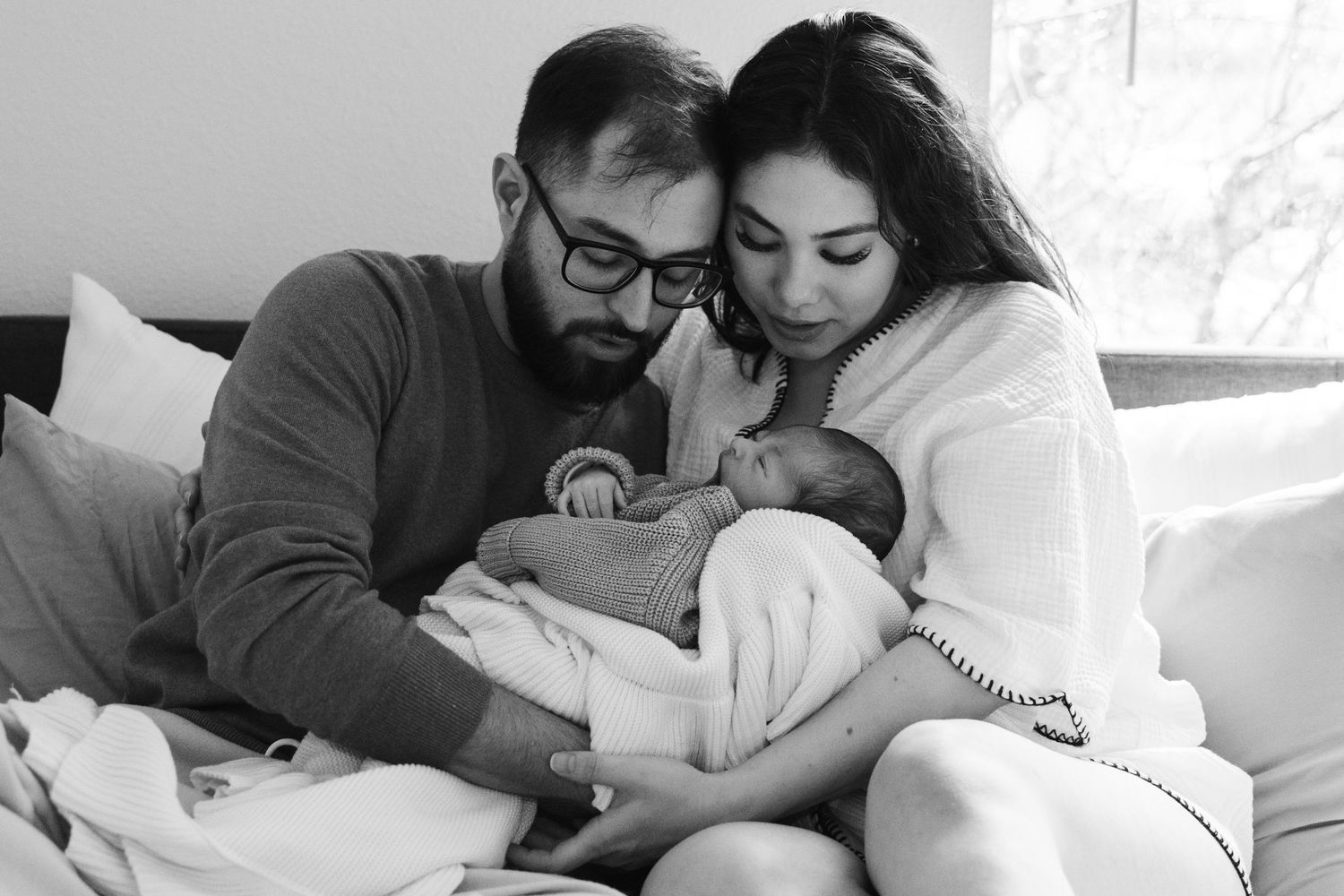 A collection of black and white photographs showing tender moments between parents and newborn babies.