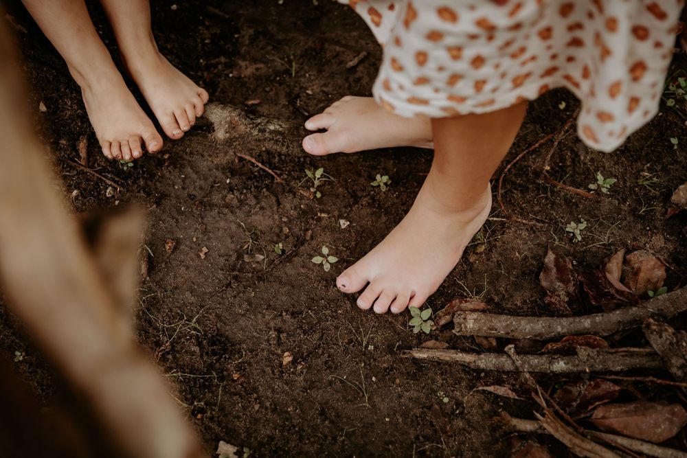 Bare feet walking together on dark soil in an intimate outdoor setting.