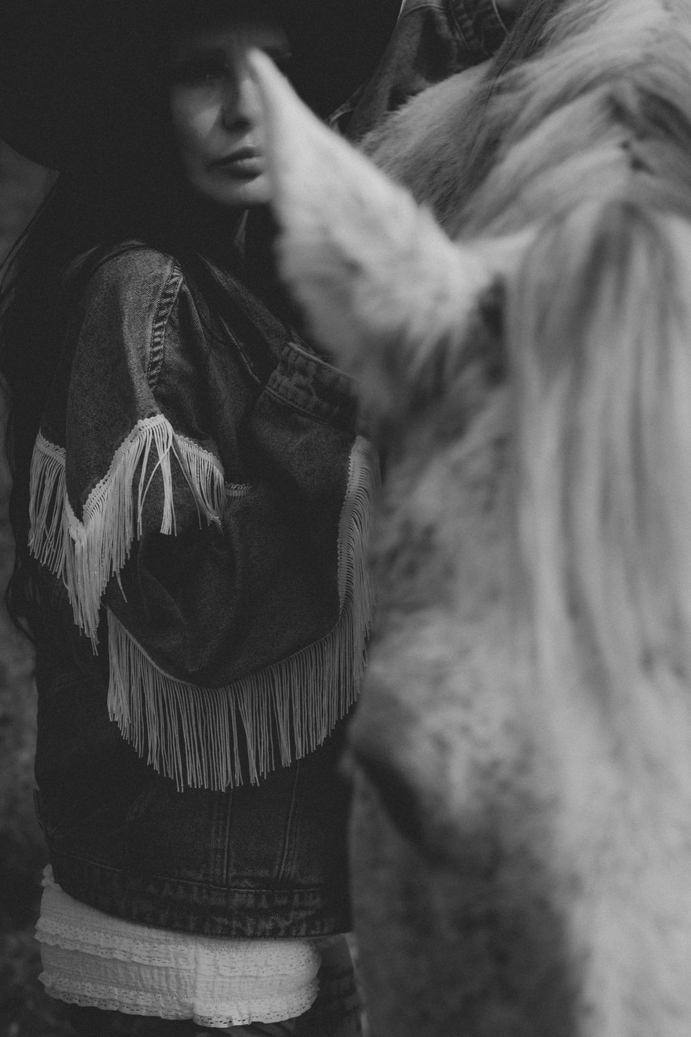 Black and white photograph series showing close-up details of a fringed leather jacket against a blurred background.