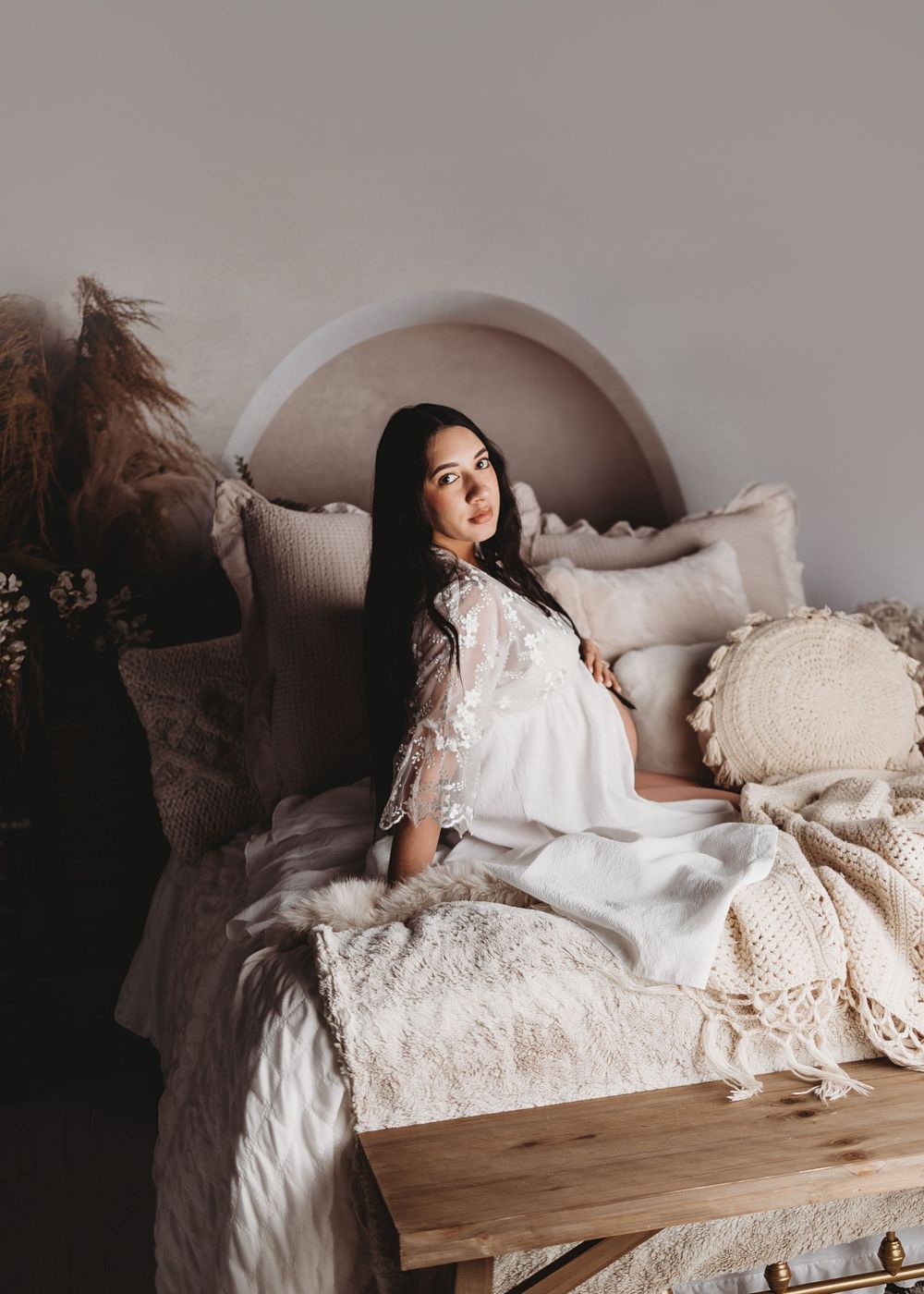 Ethereal boudoir photos on white bed with lace details and soft lighting.