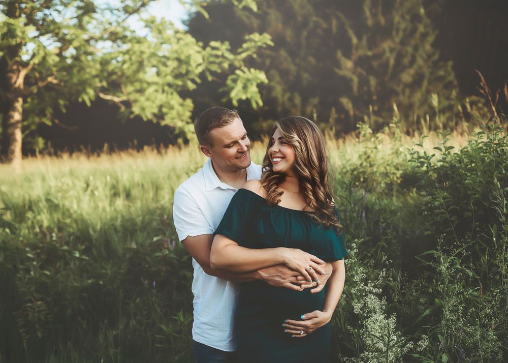 Romantic outdoor maternity photos in natural setting during golden hour.