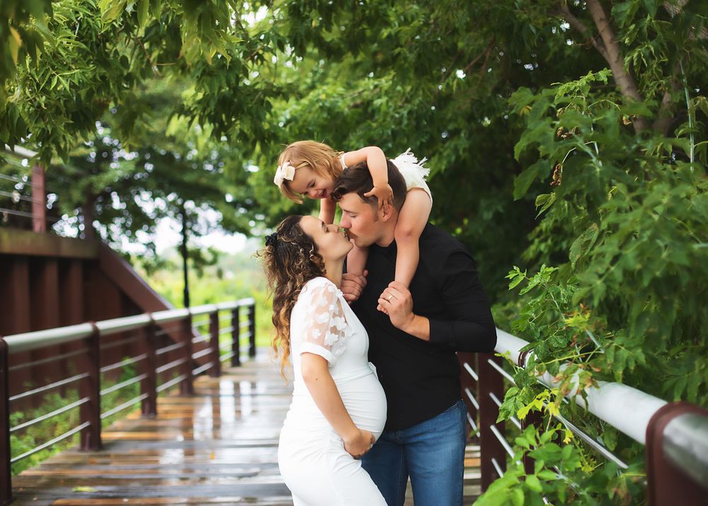 Family sharing joyful moment on wooden bridge surrounded by green foliage.