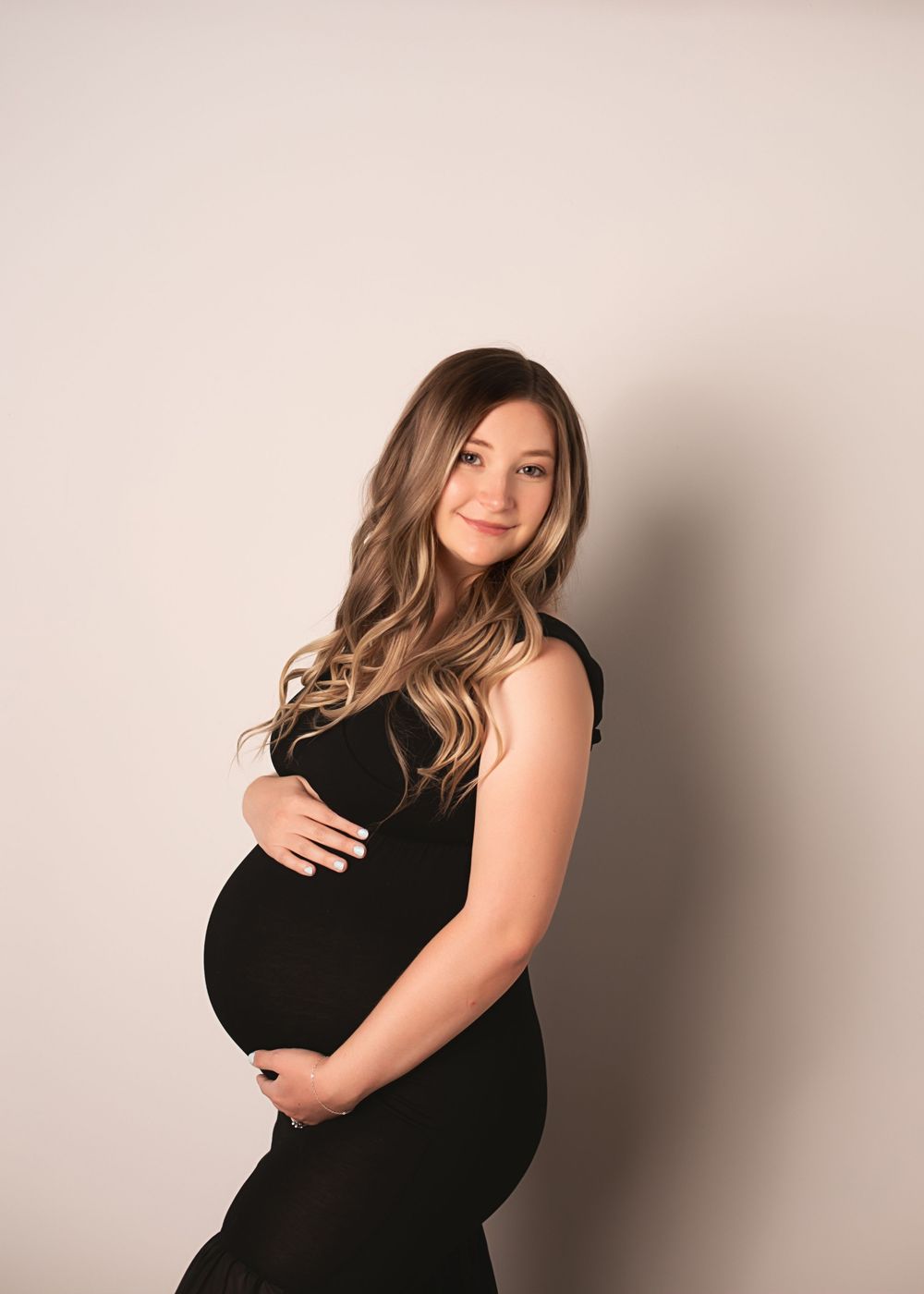 Studio maternity portraits with dramatic lighting against a neutral background.