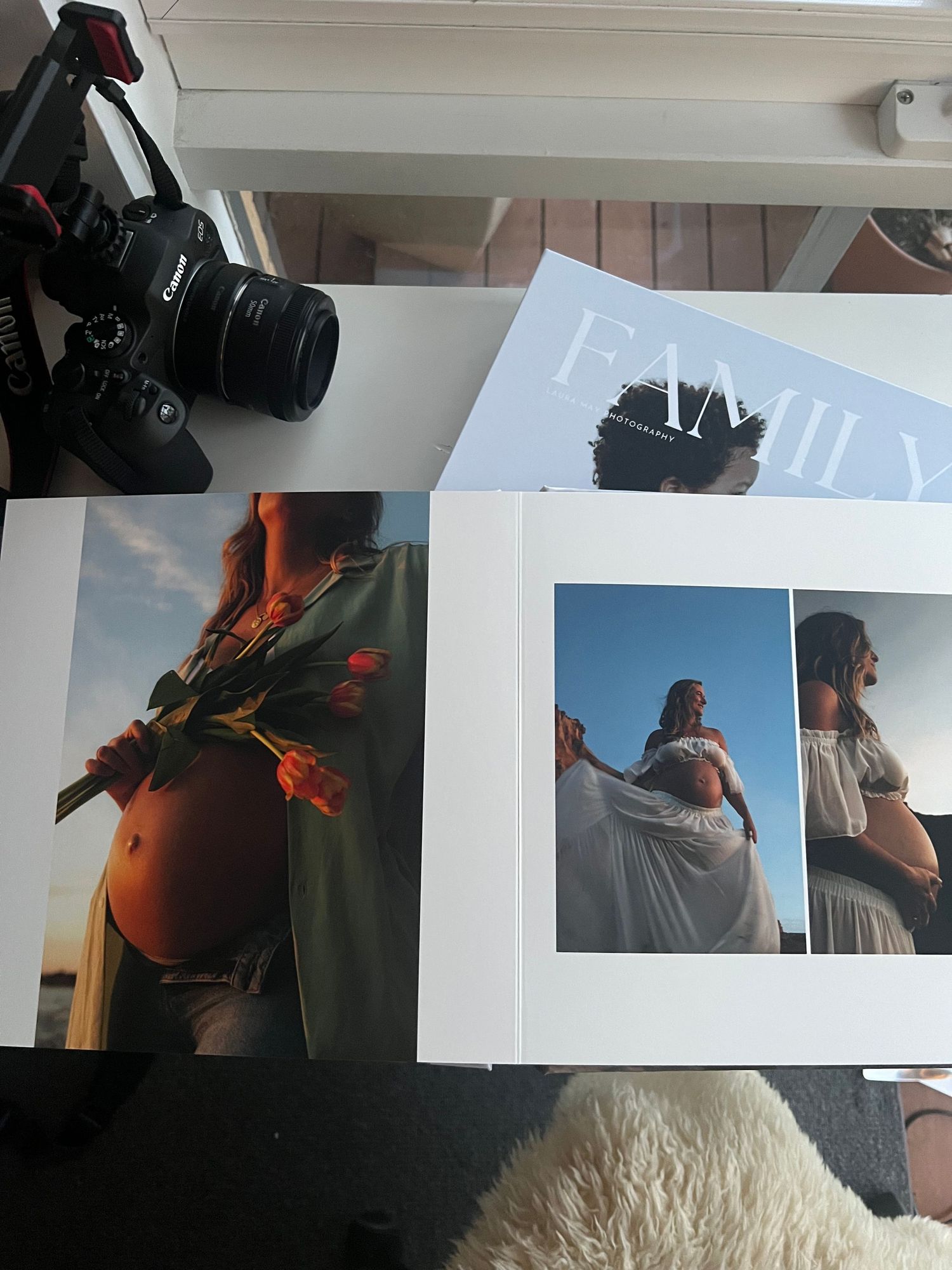 A series of black and white photo prints displayed on a white wall showing various artistic portrait compositions.