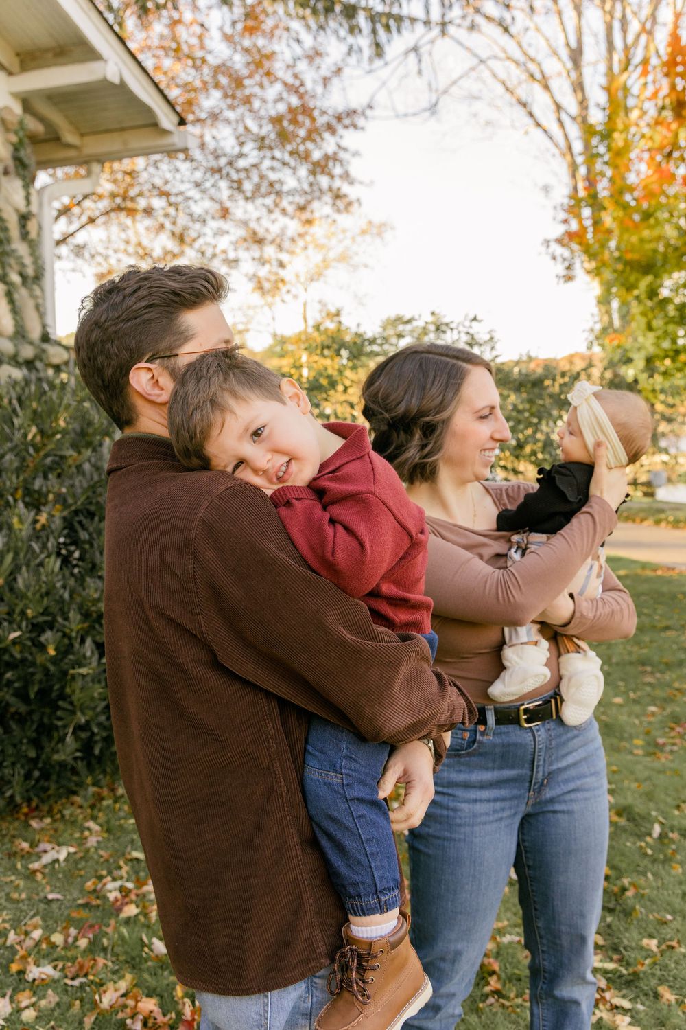 Family shares playful candid moments together during outdoor autumn photoshoot at sunset.