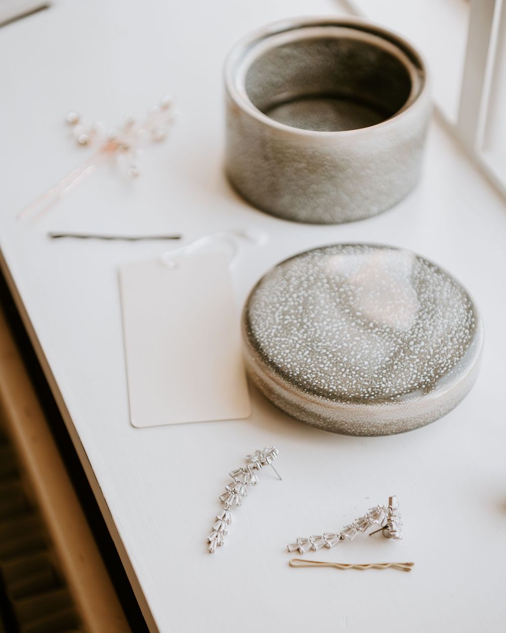 Elegant bridal jewelry flat lay featuring crystal hair pins, earrings, and a decorative gray jewelry box.
