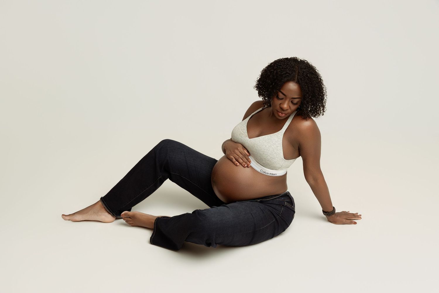 A person in a white shirt and light jeans poses gracefully on a light gray backdrop in a fashion photography series.