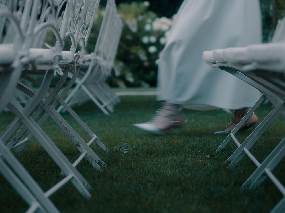 White folding chairs arranged on a lush green lawn for an outdoor event.