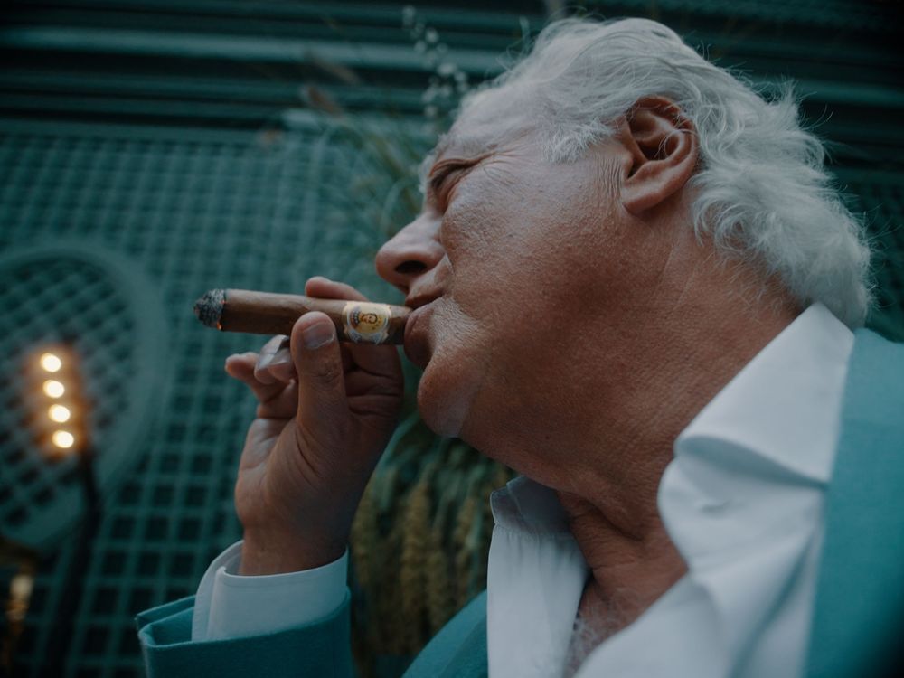 Person in a dark setting takes multiple sips from a white cup with dramatic lighting and teal tones.