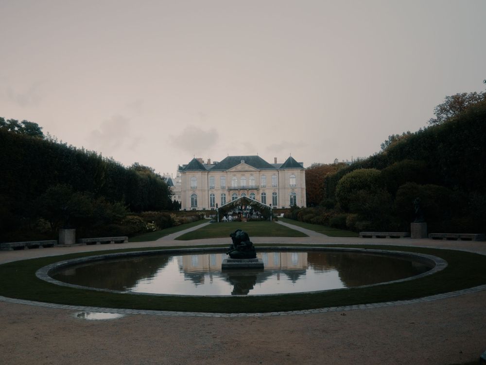 A panoramic view of a grand estate with reflecting pools and manicured gardens at dusk.