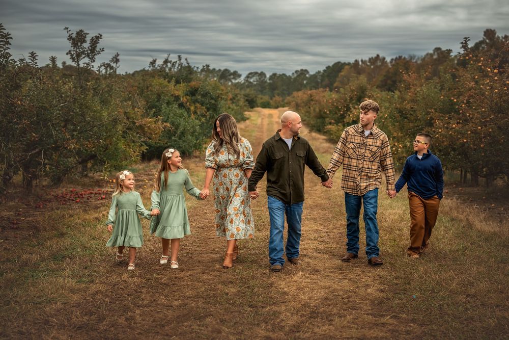 A group of people walking together on a rustic dirt path through autumn foliage during golden hour.