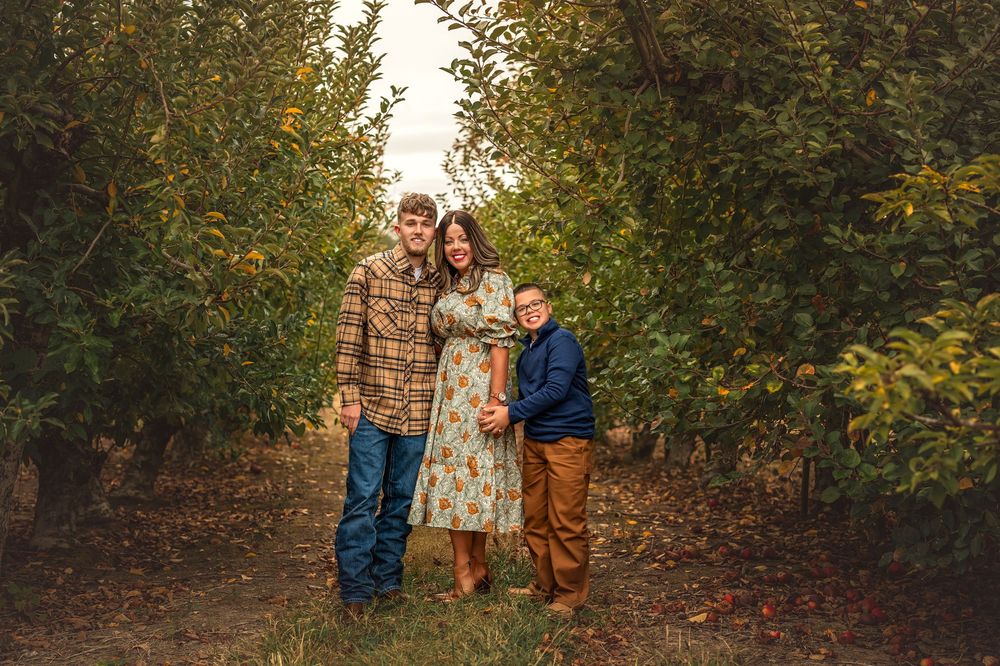 Family poses together in a fall garden setting with autumn foliage and brick wall backdrop.