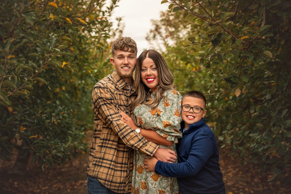 A couple shares an intimate moment outdoors during an autumn photoshoot with golden foliage in the background.