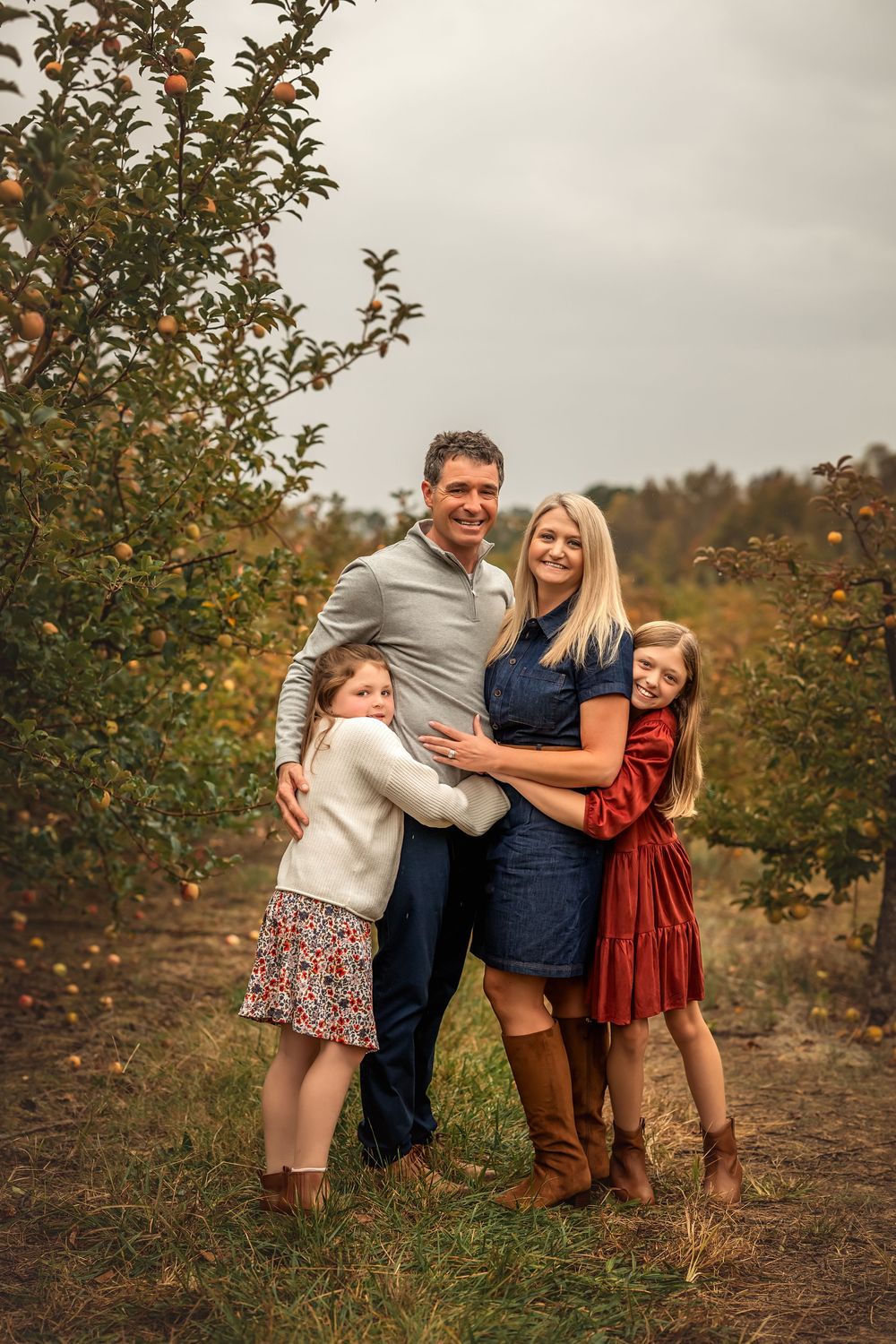 A candid family moment captured in an apple orchard during fall with coordinated outfits.