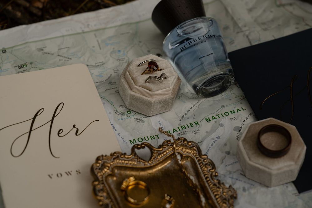 Wedding details including rings, calligraphy, and perfume bottles arranged on a surface.