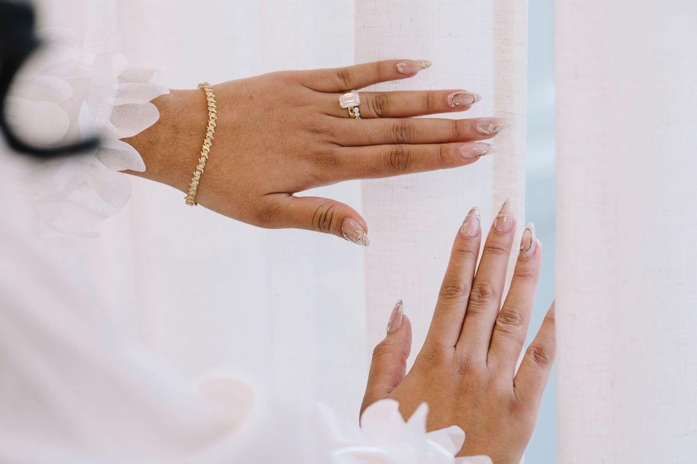 Hands applying white nail polish to fingernails in a manicure sequence showing multiple steps of the process.
